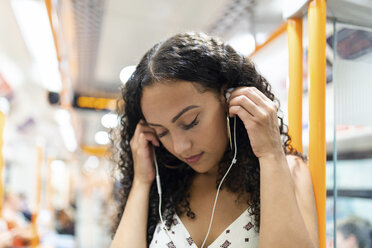 Young woman listening to music with earphones on the subway train - WPEF00803