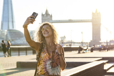 UK, London, smiling young woman taking a selfie with Tower Bridge in background - WPEF00820