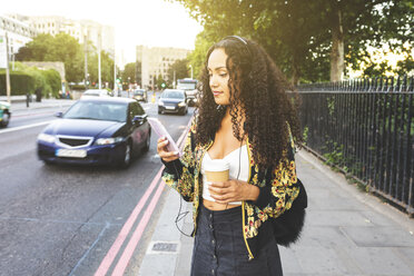 UK, London, young woman with cell phone on the pavement in the city - WPEF00827