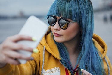 Porträt einer jungen Frau mit gefärbten blauen Haaren, die ein Selfie mit ihrem Smartphone macht - VPIF00852