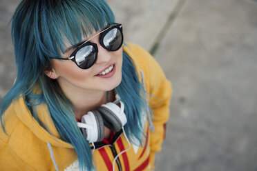 Porträt einer jungen Frau mit blau gefärbtem Haar und Kopfhörern, die nach oben schaut - VPIF00863