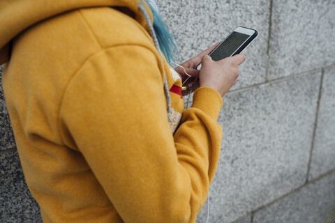 Junge Frau mit gefärbten blauen Haaren benutzt ein Smartphone, Teilansicht, lizenzfreies Stockfoto