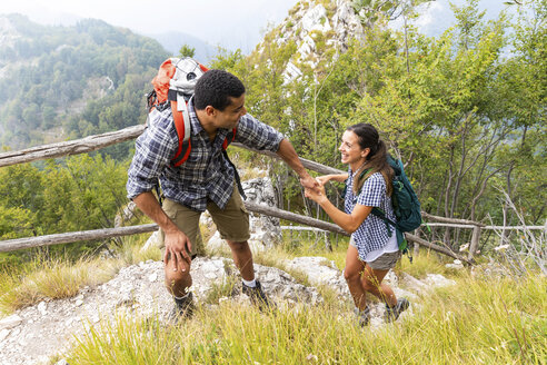 Italien, Massa, Mann hilft einer jungen Frau beim Besteigen einer Stufe beim Wandern in den Alpi Apuane - WPEF00852