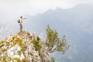 Italy, Massa, man standing on top of a peak in the Alpi Apuane mountains - WPEF00854