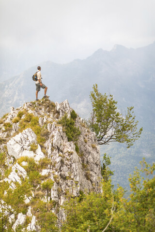 Italien, Massa, Mann steht auf einem Gipfel in den Alpi Apuane, lizenzfreies Stockfoto