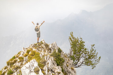 Italy, Massa, man cheering on top of a peak in the Alpi Apuane mountains - WPEF00856