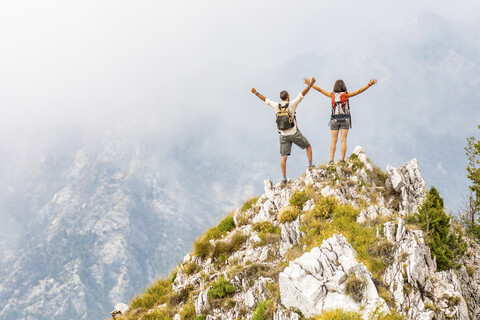 Italien, Massa, glückliches Paar jubelt auf einem Gipfel in den Alpi Apuane, lizenzfreies Stockfoto