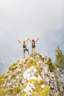 Italy, Massa, happy couple cheering on top of a peak in the Alpi Apuane mountains - WPEF00860