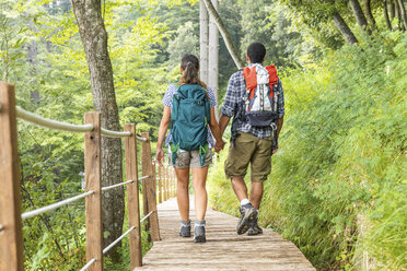 Italy, Massa, rear view of young couple hiking and walking on a boardwalk in the Alpi Apuane - WPEF00880