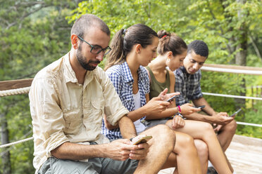 Italien, Massa, Wanderer in den Alpi Apuane, die auf ihre Smartphones schauen und auf einer Bank sitzen - WPEF00884