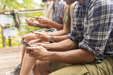 Italien, Massa, Wanderer in den Alpi Apuane, die auf ihre Smartphones schauen und auf einer Bank sitzen - WPEF00887