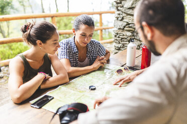 Group of hikers sitting together planning a hiking route looking at map - WPEF00896