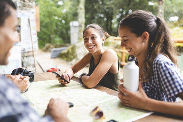 Group of hikers sitting together planning a hiking trip with a map - WPEF00900