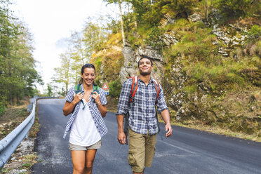 Italy, Massa, smiling young couple walking on asphalt road in the Alpi Apuane mountains - WPEF00913