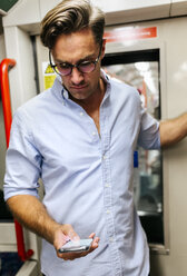 UK, London, businessman in underground train looking at cell phone - MGOF03794