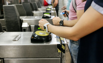 Junge Frau bezahlt mit ihrer Smartwatch in der U-Bahn, Teilansicht - MGOF03801