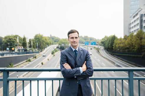 Porträt eines selbstbewussten Geschäftsmannes auf einer Autobahnbrücke - MOEF01388