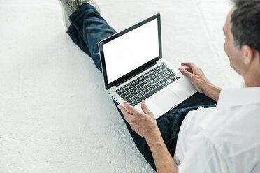 Geschäftsmann sitzt auf dem Boden und benutzt einen Laptop - MOEF01403