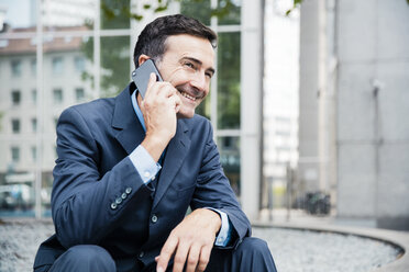 Smiling businessman on cell phone in the city - MOEF01420