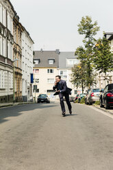 Geschäftsmann am Handy beim Inline-Skaten in der Stadt - MOEF01444