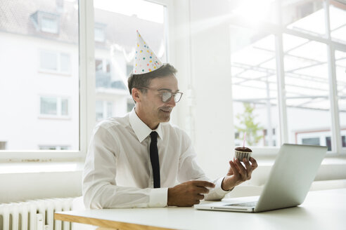Geschäftsmann mit Laptop feiert Geburtstag im Büro - MOEF01459