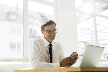 Geschäftsmann mit Laptop feiert Geburtstag im Büro - MOEF01460