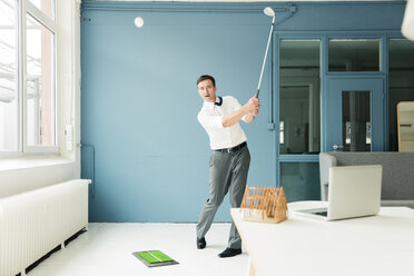 Businessman playing golf in office - MOEF01462