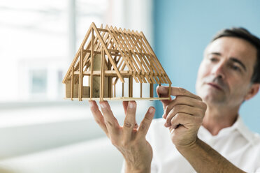 Geschäftsmann hält Modellhaus im Büro - MOEF01480