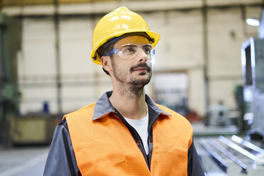 Mann in Arbeitsschutzkleidung sieht sich in einer Fabrik um - BSZF00587
