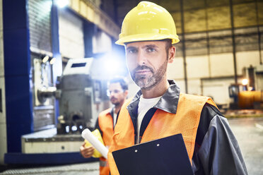 Porträt eines selbstbewussten Mannes in Arbeitsschutzkleidung in einer Fabrik - BSZF00593