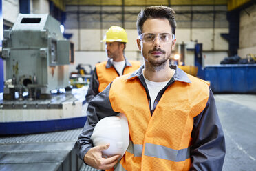 Porträt eines ernsten Mannes mit Arbeitsschutzkleidung in einer Fabrik - BSZF00596