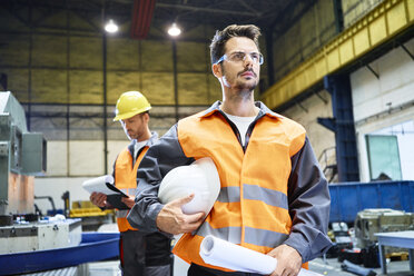 Zwei Männer in Arbeitsschutzkleidung sehen sich in einer Fabrik um - BSZF00598