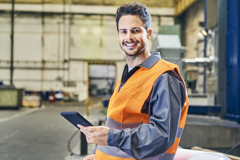 Porträt eines lächelnden Mannes mit einem Tablet in einer Fabrik - BSZF00600