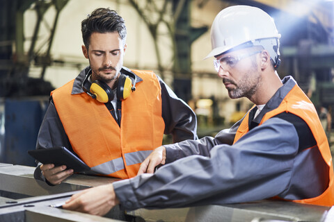 Two men wearing protective workwear working in factory stock photo