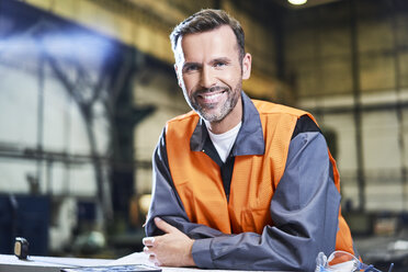 Porträt eines lächelnden Mannes in einer Fabrik mit Sicherheitsweste - BSZF00617