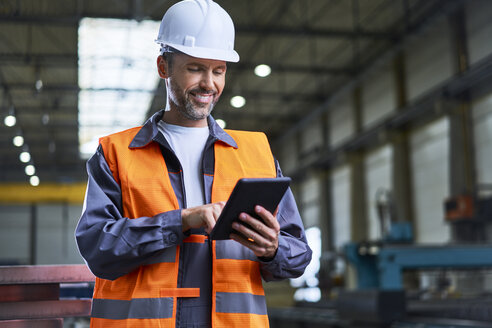 Smiling man using tablet in factory - BSZF00623