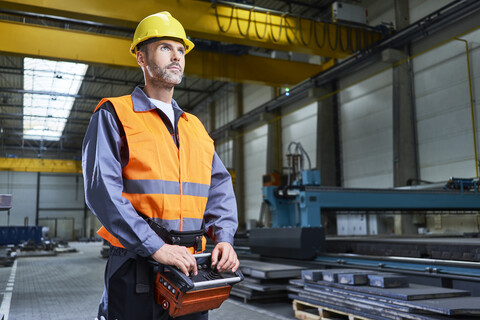 Portrait of man in factory operating machinery with remote console stock photo