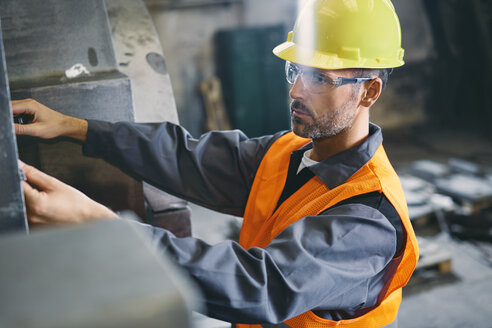 Mann in Arbeitsschutzkleidung bei der Arbeit in einer Fabrik - BSZF00629