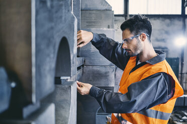 Mann in Arbeitsschutzkleidung bei der Arbeit in einer Fabrik - BSZF00631