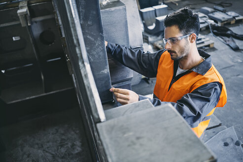 Mann in Arbeitsschutzkleidung bei der Arbeit in einer Fabrik - BSZF00632