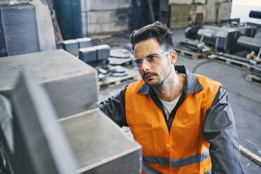 Mann in Arbeitsschutzkleidung bei der Arbeit in einer Fabrik - BSZF00634