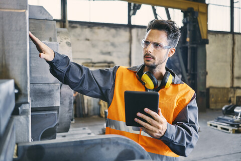 Man with tablet wearing protective workwear working in factory stock photo