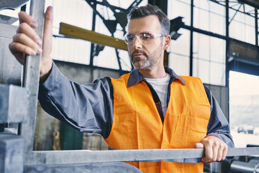 Mann in Arbeitsschutzkleidung bei der Arbeit in einer Fabrik - BSZF00645