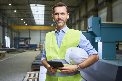 Porträt eines selbstbewussten Mannes mit Hemd und Sicherheitsweste in einer Fabrik, lizenzfreies Stockfoto