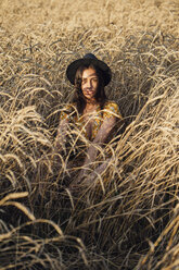 Porträt einer jungen Frau mit Hut in einem Maisfeld sitzend - VPIF00873