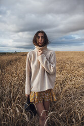 Porträt einer jungen Frau, die einen übergroßen Rollkragenpullover trägt und in einem Maisfeld steht - VPIF00877