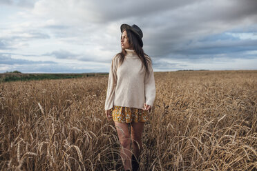 Junge Frau mit Hut und übergroßem Rollkragenpullover geht in einem Maisfeld spazieren - VPIF00879