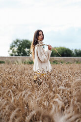 Young woman wearing oversized turtleneck pullover standing in corn field - VPIF00881