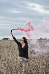 Junge Frau in einem Maisfeld stehend mit Rauchfackel - VPIF00898