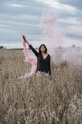 Porträt einer jungen Frau in einem Maisfeld mit Rauchfackel - VPIF00899